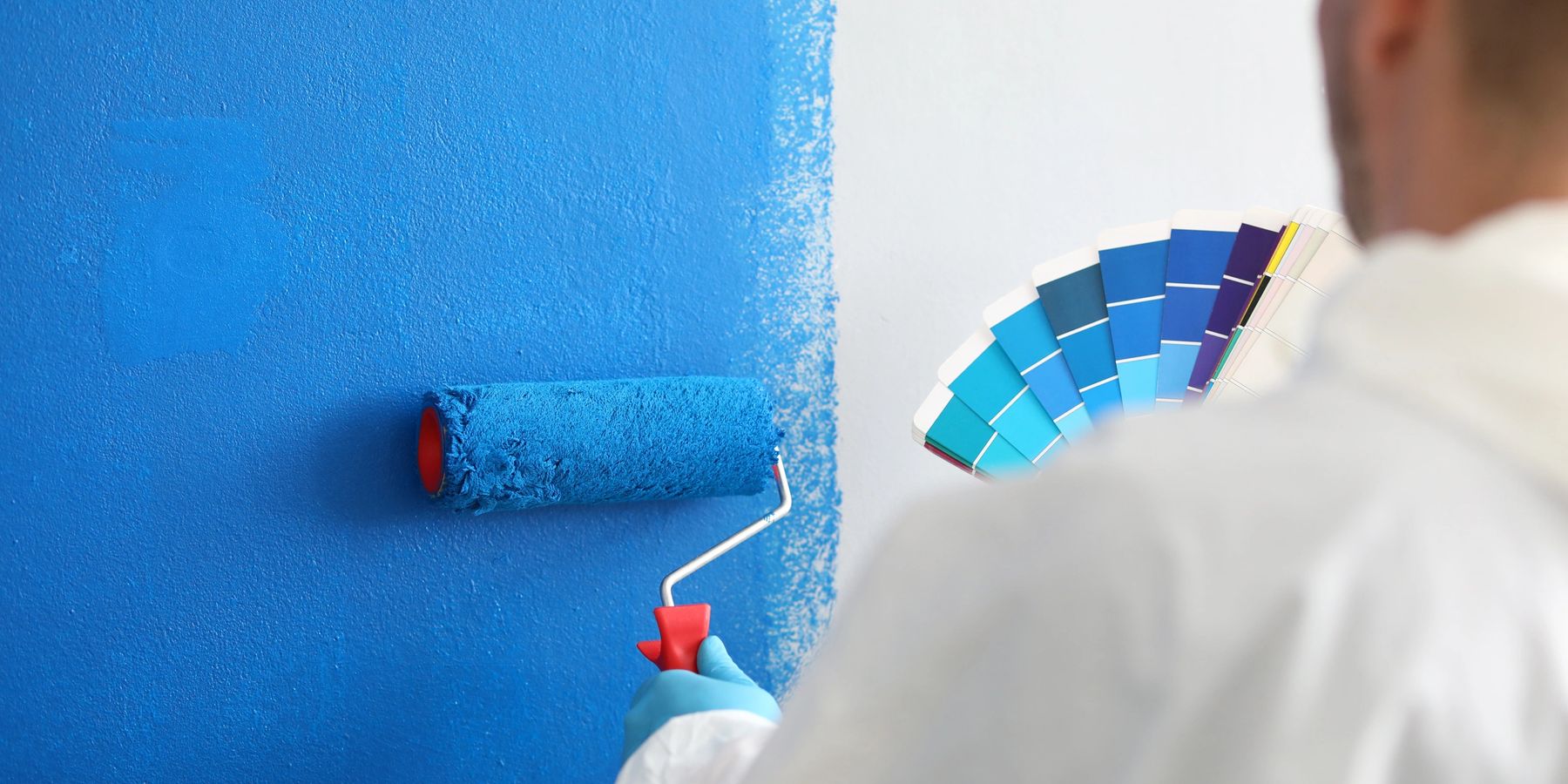 Artesano con rodillo aplicando pintura en pared